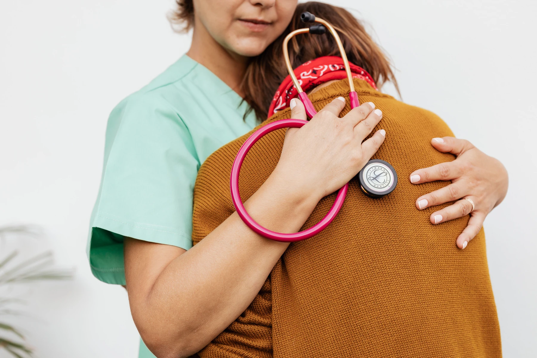 A healthcare professional with a stethoscope offering a comforting embrace